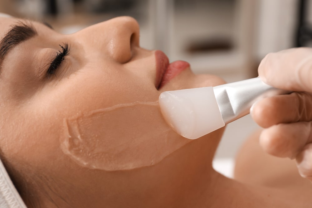 Young woman during face peeling procedure in salon